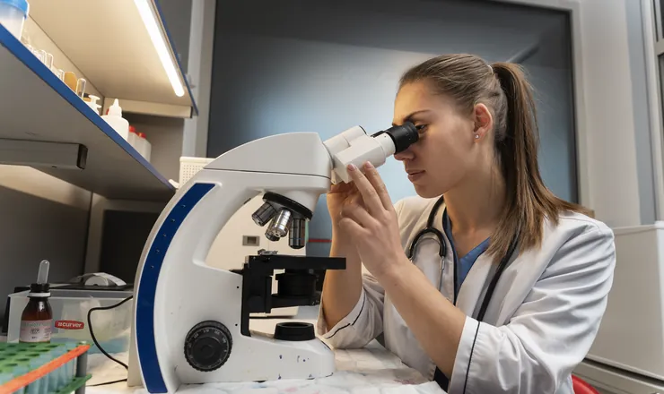 Veterinária analisando um exame no microscópio